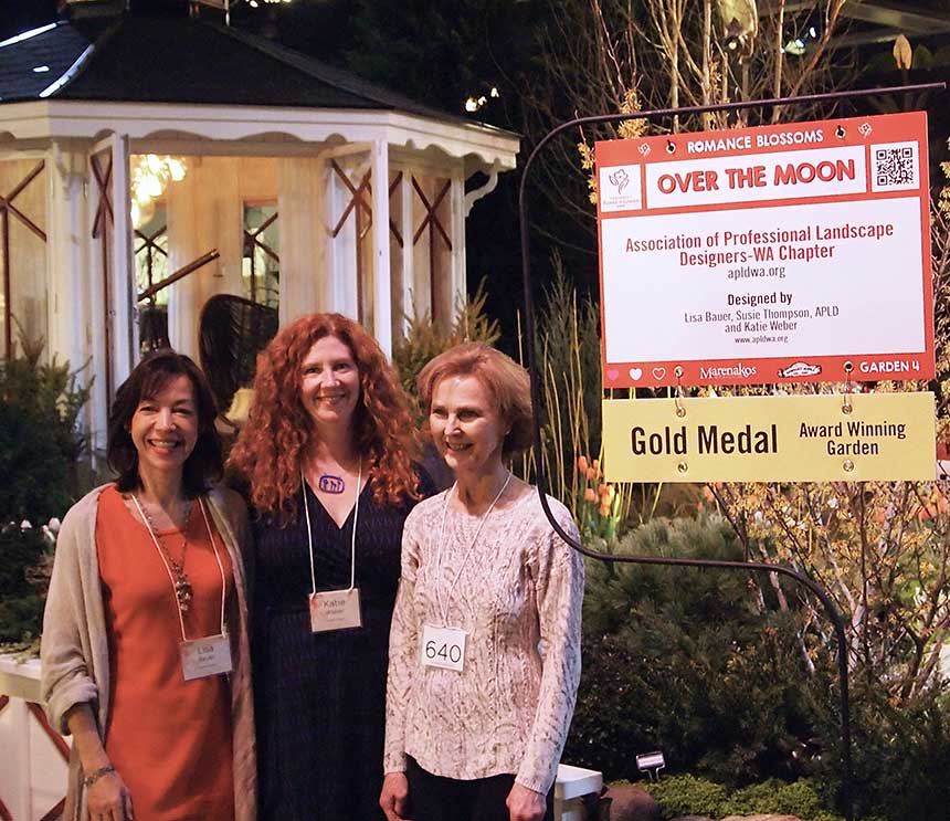 Design team standing in front of the garden, next to the award sign.