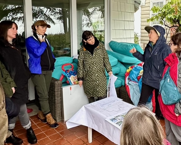 Members standing around and discussing landscape plans on a table.