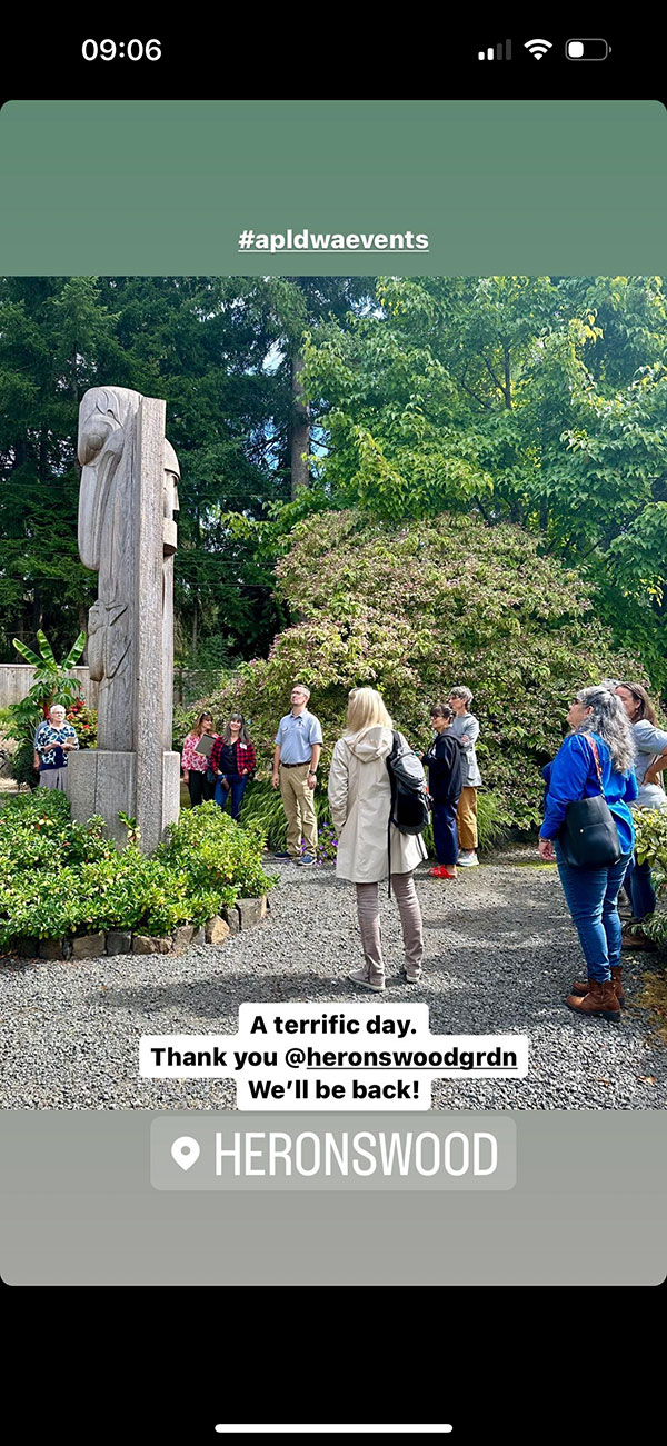 Group of people observing a native pole carving (sculpture)