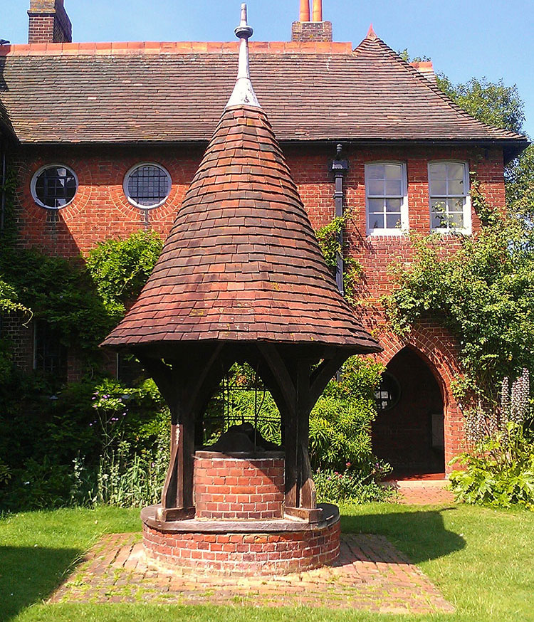 Red brick well in front of the Arts and Crafts period Morris Red House